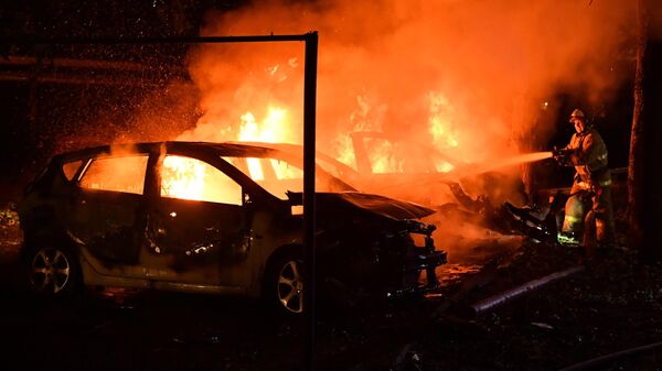 Сотрудник противопожарной службы МЧС ДНР тушит автомобили, сгоревшие в результате обстрела ВСУ в Донецке