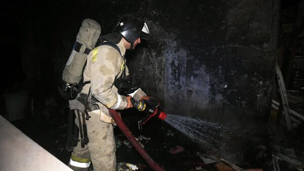 Сотрудники МЧС во время тушения пожара в доме, пострадавшем от обстрела ВСУ в Донецке
