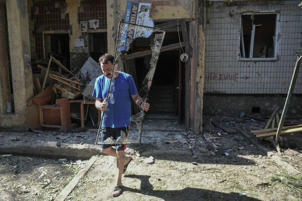 Мужчина выносит разбитое стекло у поврежденного жилого дома в Петровском районе Донецка после обстрелов украинскими войсками