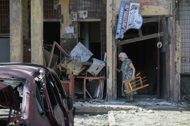Женщина у подъезда поврежденного жилого дома в Петровском районе Донецка после обстрелов украинскими войсками
