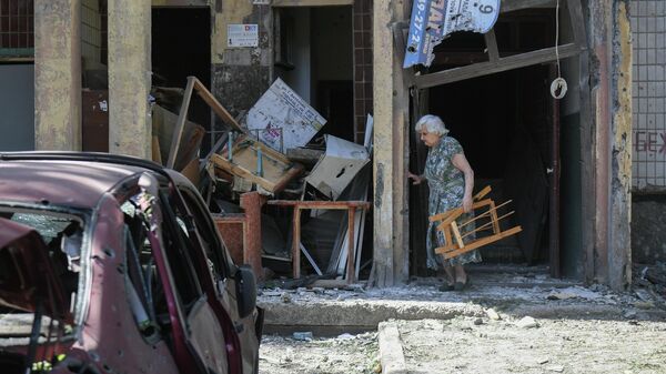 Женщина у подъезда поврежденного жилого дома в Петровском районе Донецка