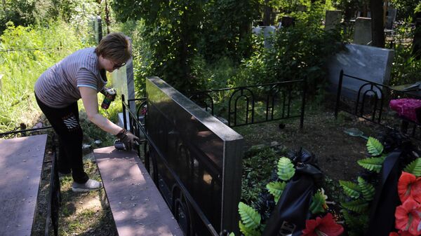 Женщина убирается на могиле в Троицкую родительскую субботу