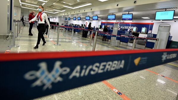Персонал аэропорта проходит мимо стоек регистрации в аэропорту Белграда