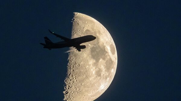 Самолет в небе на фоне луны
