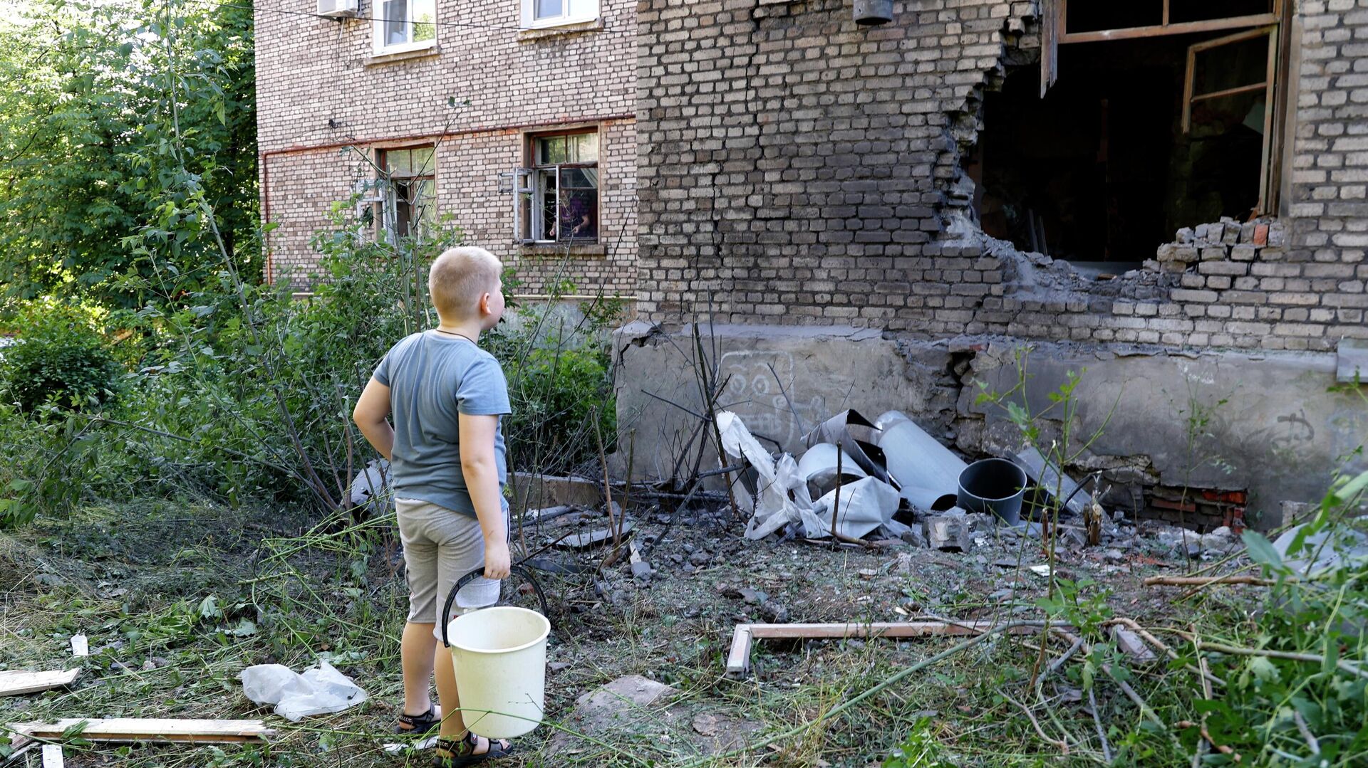 Мальчик возле дома, поврежденного в результате обстрела ВСУ Донецка - РИА Новости, 1920, 13.06.2022