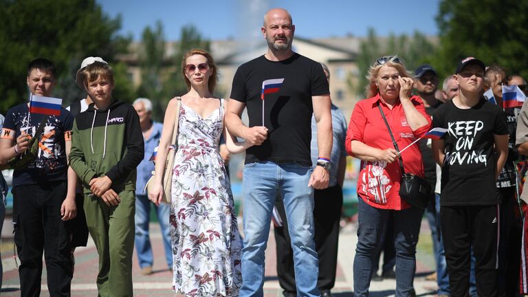 Горожане во время поднятия большого российского флага в честь празднования Дня России на главной площади Мелитополя