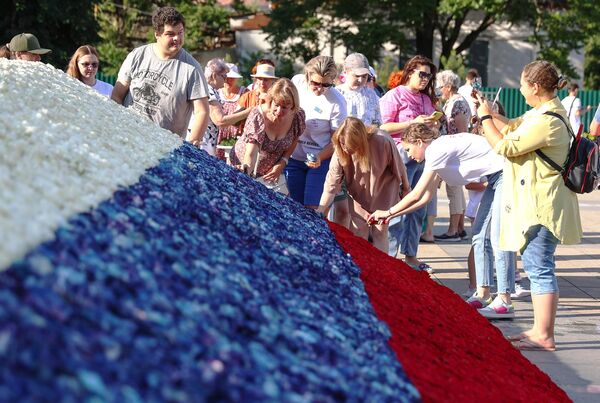 Женщины участвуют в создании государственного флага из 50 тысяч бутонов роз в День России в Краснодаре