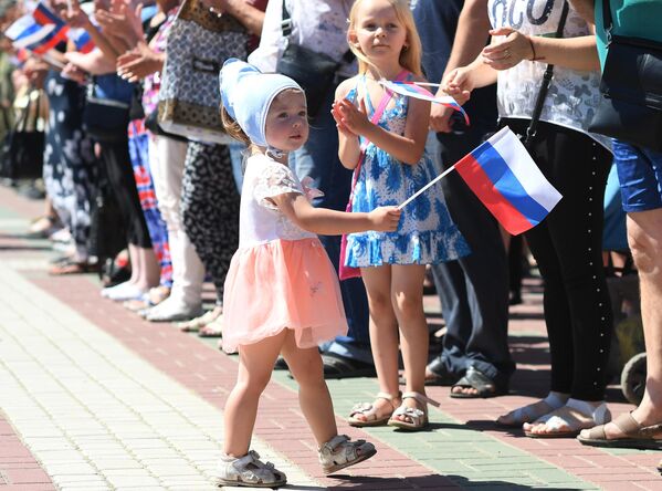 Девочка с российским триколором во время поднятия большого российского флага в честь празднования Дня России на главной площади Мелитополя