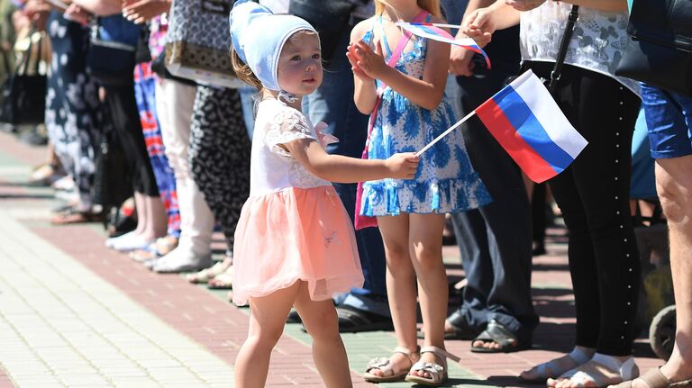 Девочка с российским триколором во время поднятия большого российского флага в честь празднования Дня России на главной площади Мелитополя