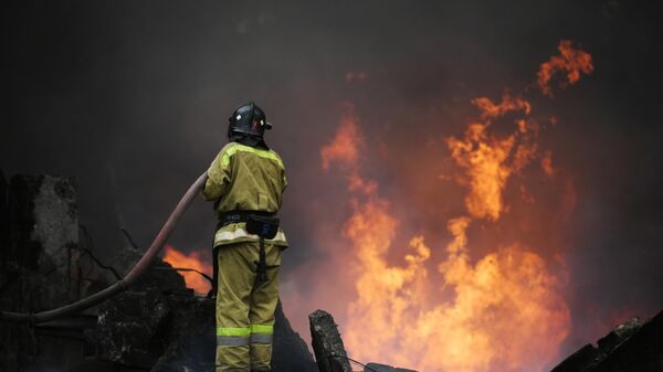 Сотрудник МЧС ДНР тушит пожар в Донбассе.