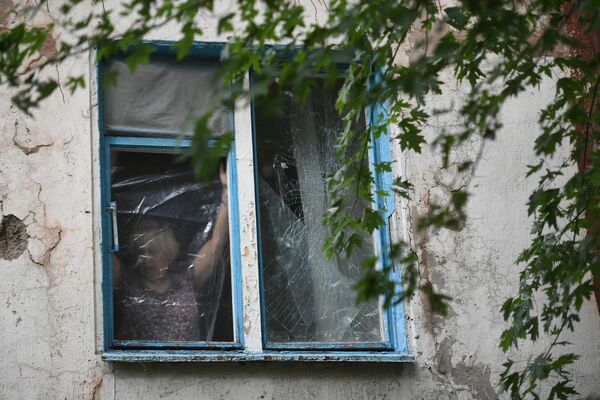 Женщина затягивает полиэтиленовой пленкой окно, разбитое в результате обстрелов  ВСУ Донецка.