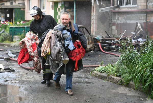 Мужчина выносит уцелевшие вещи из дома, где возник пожар в результате обстрелов со стороны ВСУ Донецка