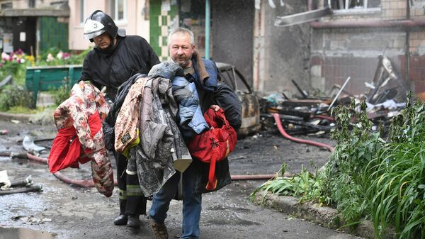 Мужчина выносит уцелевшие вещи из дома, где возник пожар в результате обстрелов со стороны ВСУ Донецка