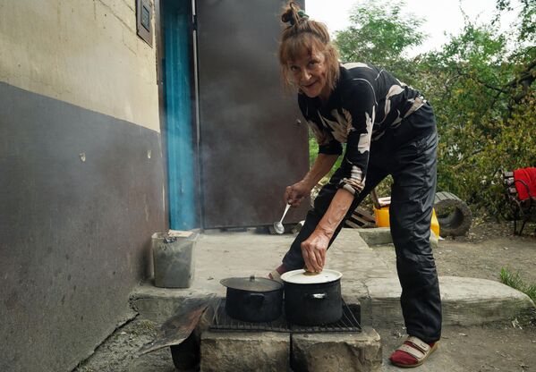 Местная жительница готовит пищу на костре возле подъезда одного из жилых домов в Северодонецке