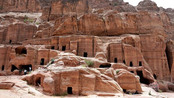 Туристы осматривают гробницы в древнем городе Петра в Иордании