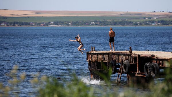Отдыхающие прыгают с пирса в море на пляже в поселке Сенной в Краснодарском крае