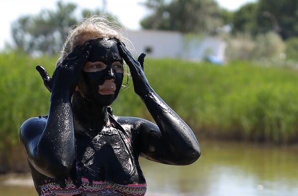 Девушка мажет лицо грязью на грязевом озере в станице Голубицкой в Краснодарском крае