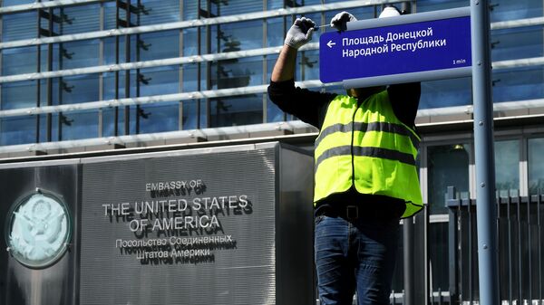 Сотрудник коммунальной службы во время монтажа адресного указателя площади Донецкой Народной Республики возле здания посольства США в Москве