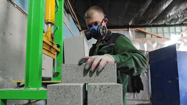 Рабочий в цехе завода по изготовлению гиперпрессованных строительных материалов