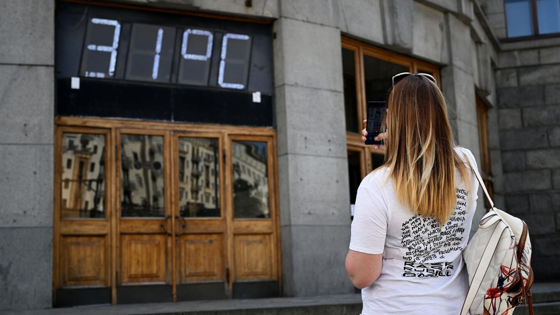 Девушка фотографирует на смартфон градусник на фасаде здания Центрального телеграфа на Тверской улице в Москве - РИА Новости, 1920, 04.08.2022