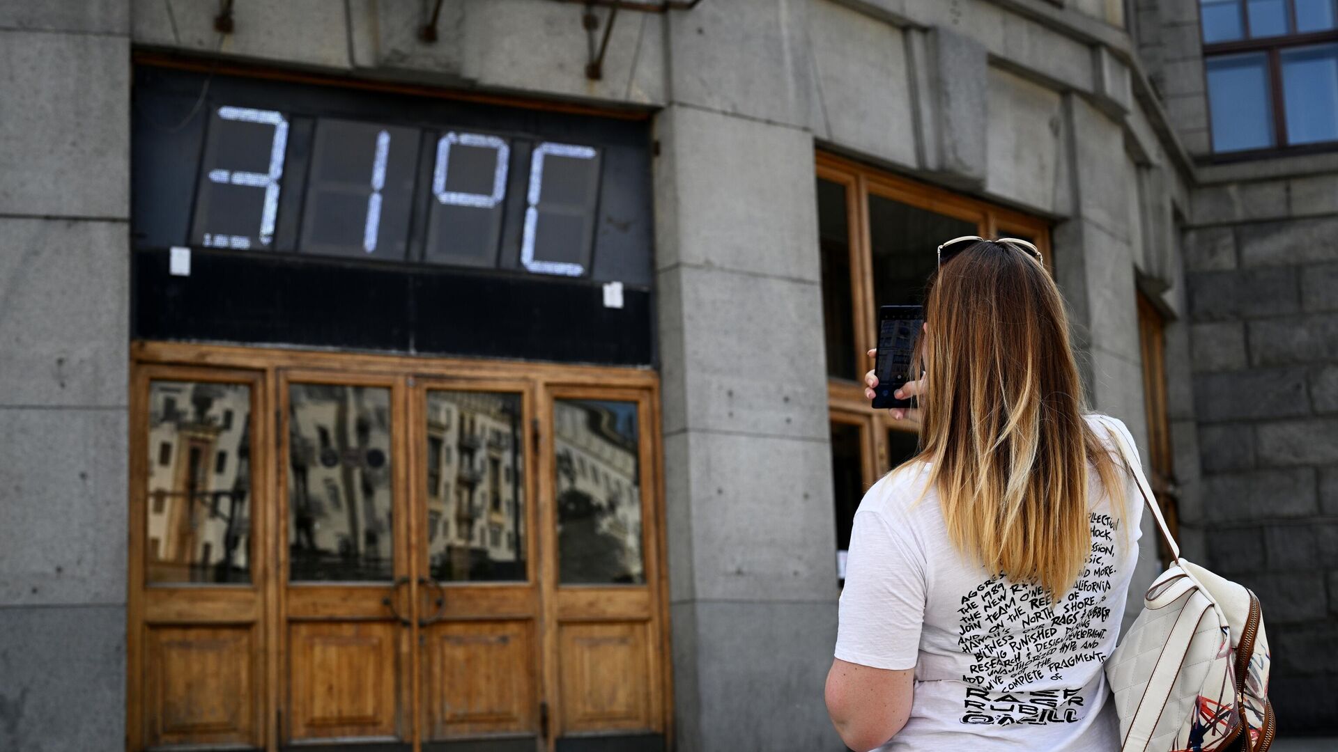 Девушка фотографирует на смартфон градусник на фасаде здания Центрального телеграфа на Тверской улице в Москве - РИА Новости, 1920, 07.07.2022