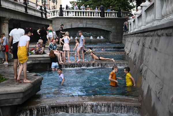 Дети купаются в фонтанах на Манежной площади в жаркую погоду в Москве 