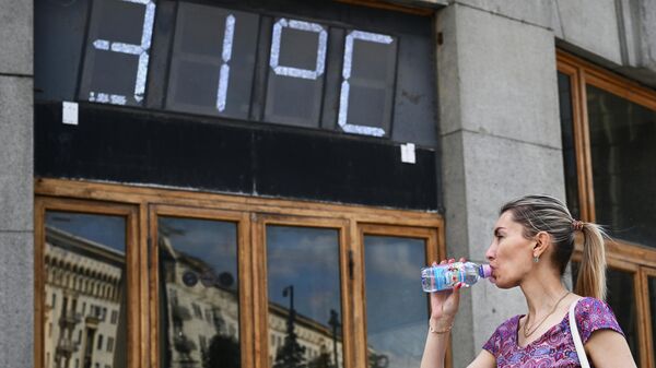Девушка пьет воду возле здания Центрального телеграфа на Тверской улице в Москве