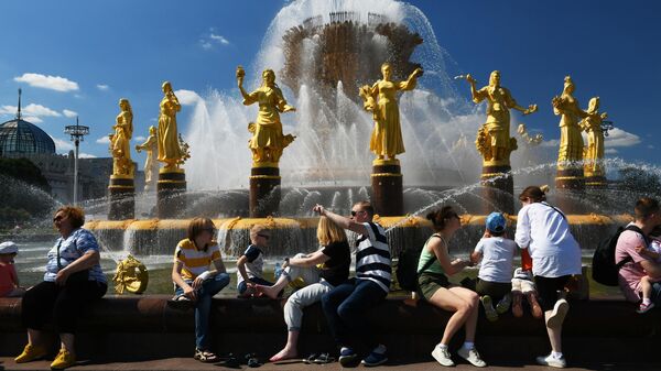 Люди в жаркую погоду возле фонтана Дружба народов на ВДНХ в Москве