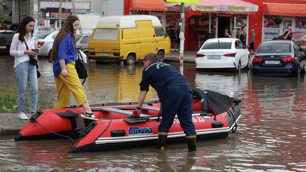 орожане на надувной лодке Службы спасения пересекают улицу в Краснодаре, затопленную после ночных ливней