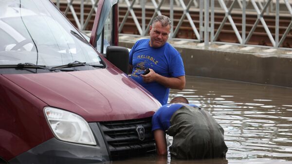 Мужчины у автомобиля на затопленной после ночного ливня улице в Краснодаре