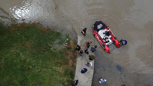 Горожане на надувной лодке Службы спасения пересекают улицу в Краснодаре, затопленную после ночных ливней