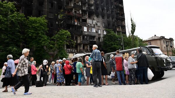 Местные жители в очереди за хлебом у передвижного пункта гуманитарной помощи возле Покровского храма в Мариуполе
