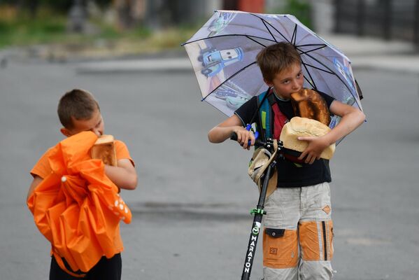 Дети едят хлеб возле передвижного пункта гуманитарной помощи возле Покровского храма в Мариуполе