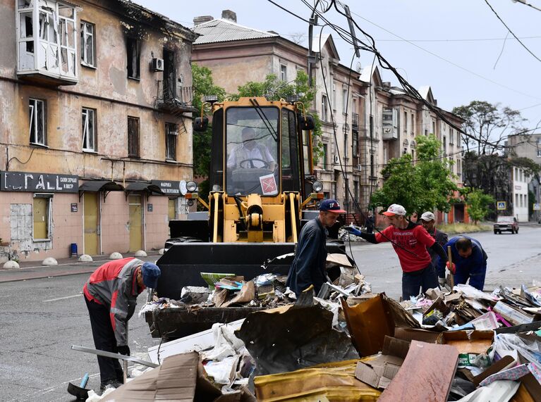 Местные жители разбирают завалы на Митрополитской улице в Мариуполе