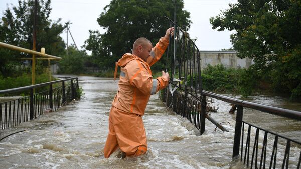 Сотрудник МЧС РФ работает на улице, затопленной после сильных дождей, в поселке Комсомольское Симферопольского района