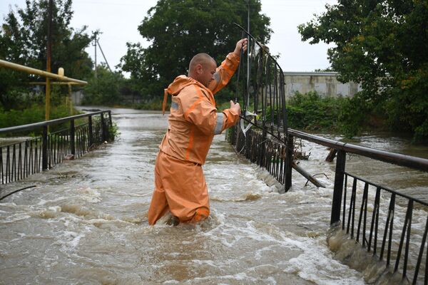 Сотрудник МЧС РФ работает на улице, затопленной после сильных дождей, в поселке Комсомольское Симферопольского района