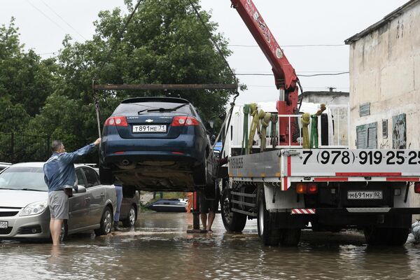 Погрузка легкового автомобиля на эвакуатор на улице, затопленной после сильных дождей, в поселке Комсомольское Симферопольского района