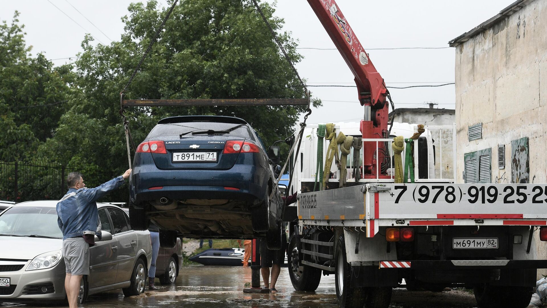 Погрузка легкового автомобиля на эвакуатор на улице, затопленной после сильных дождей, в поселке Комсомольское Симферопольского района - РИА Новости, 1920, 28.06.2022