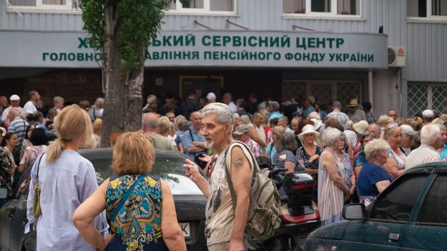 Люди стоят в очереди в офис пенсионного фонда в Херсоне, возобновившего работу