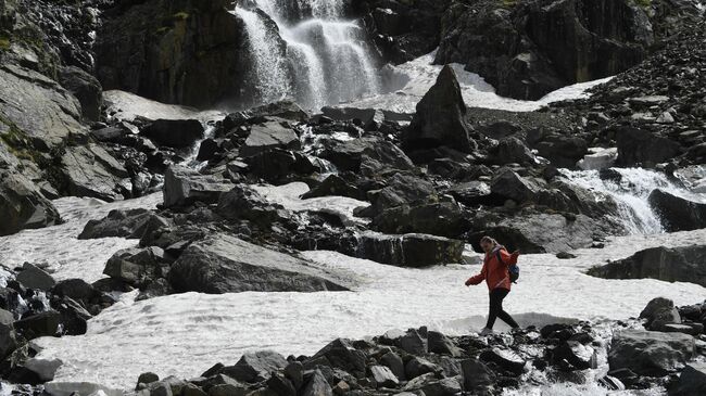 Девушка возле водопада в долине реки Актру в Республике Алтай