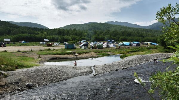 Вид на Малкинские термальные источники и палаточный лагерь отдыхающих неподалеку от реки Ключевка в Камчатском крае