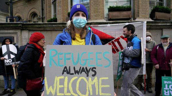 Девушка с плакатом Беженцам всегда рады на улице Лондона, Великобритания