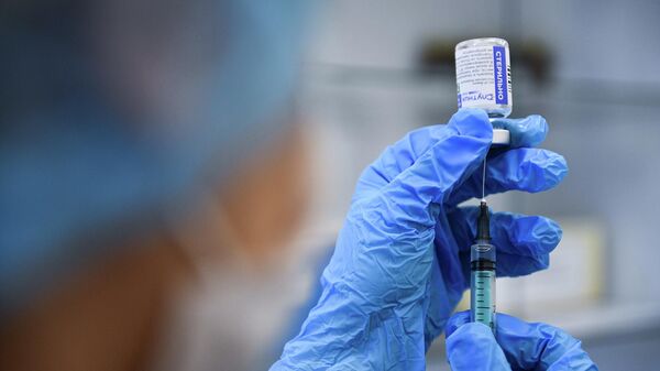 Медицинский сотрудник наполняет шприц вакциной 