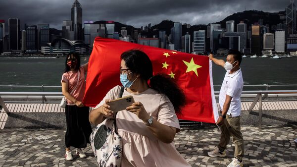 Люди держат китайский флаг в Гонконге