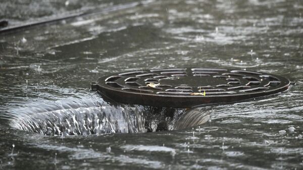 Открытый люк сточной канализации во время дождя в Москве