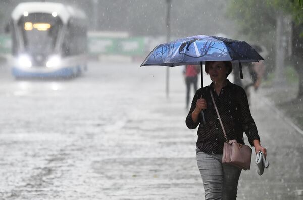 Женщина под зонтом во время дождя в Москве