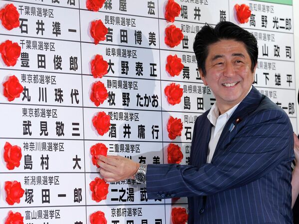 Премьер-министр Японии Синдзо Абэ ставит красную розочку на имя победившего кандидата от своей партии во время подсчета голосов на выборах в верхнюю палату парламента. 21 июля 2013 