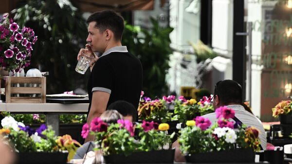 Мужчина на летней веранде кафе на Никольской улице в Москве.