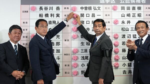 Премьер-министр Японии и лидер Либерально-демократической партии Фумио Кисида помещает бумажную розу на имя кандидата в знак победы на выборах в верхнюю палату парламента на партийном собрании