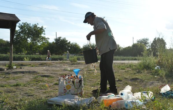 Житель разливает по бутылям воду, набранную в колодце на окраине Лисичанска
